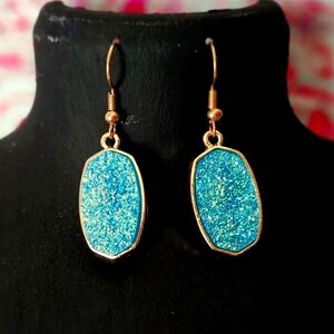 Elegant dangle earrings with sparkling blue/aqua stones and gold accents.